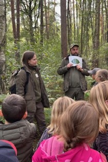 Mitarbeiter und Mitarbeiterinnen der Naturwacht und der Stiftung Heinz Sielmann erklären den Schülern Details aus dem Wald.