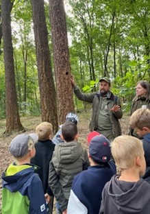 Mitarbeiter und Mitarbeiterinnen der Naturwacht und der Stiftung Heinz Sielmann erklären den Schülern Details aus dem Wald.